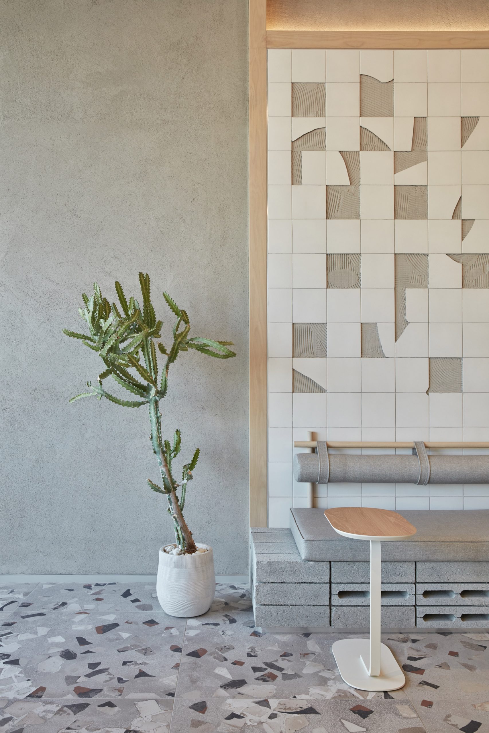 Broken-ceramics wall with green plant and terrazzo floor in Drop Coffee