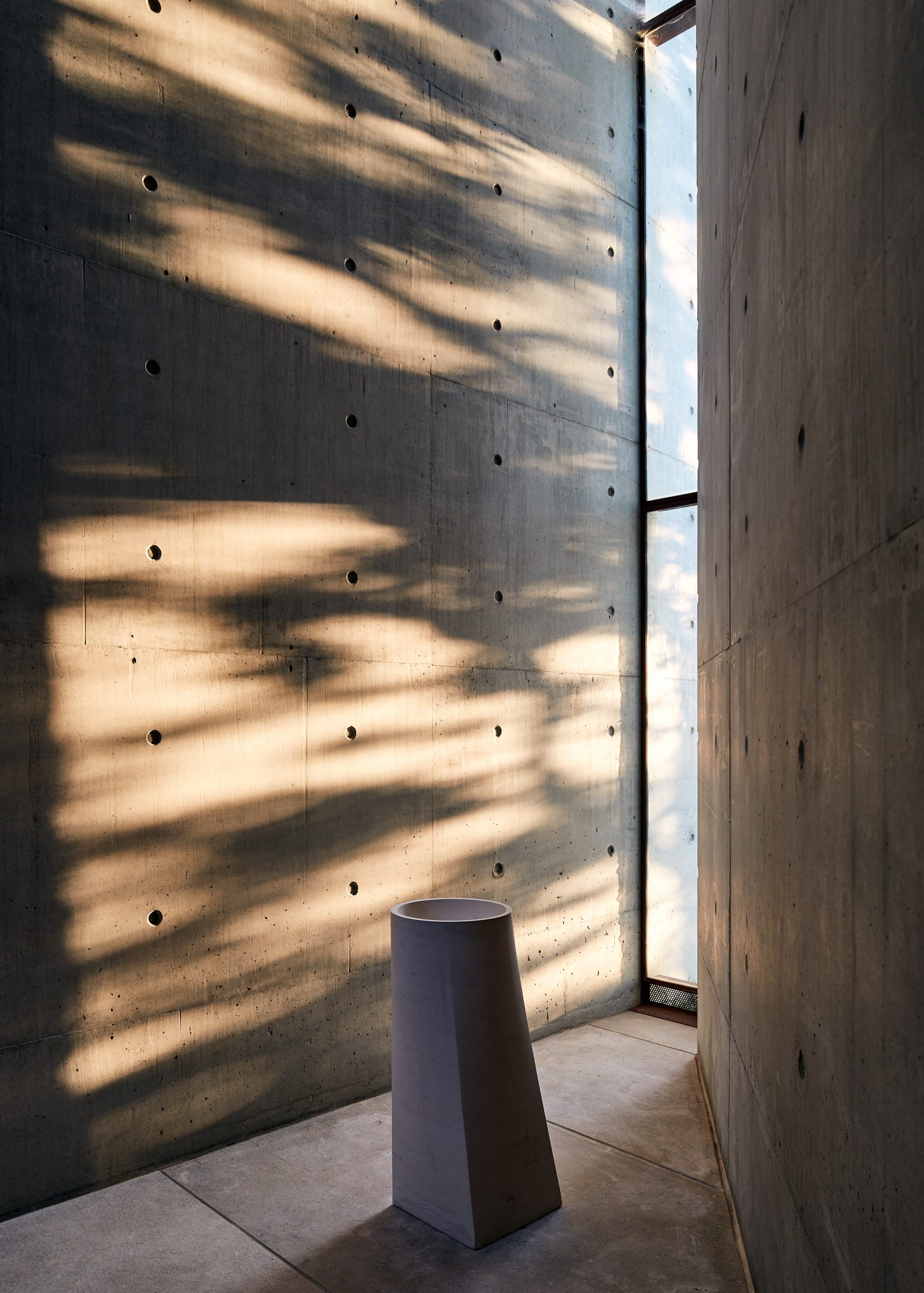 A narrow window lighting a concrete room 