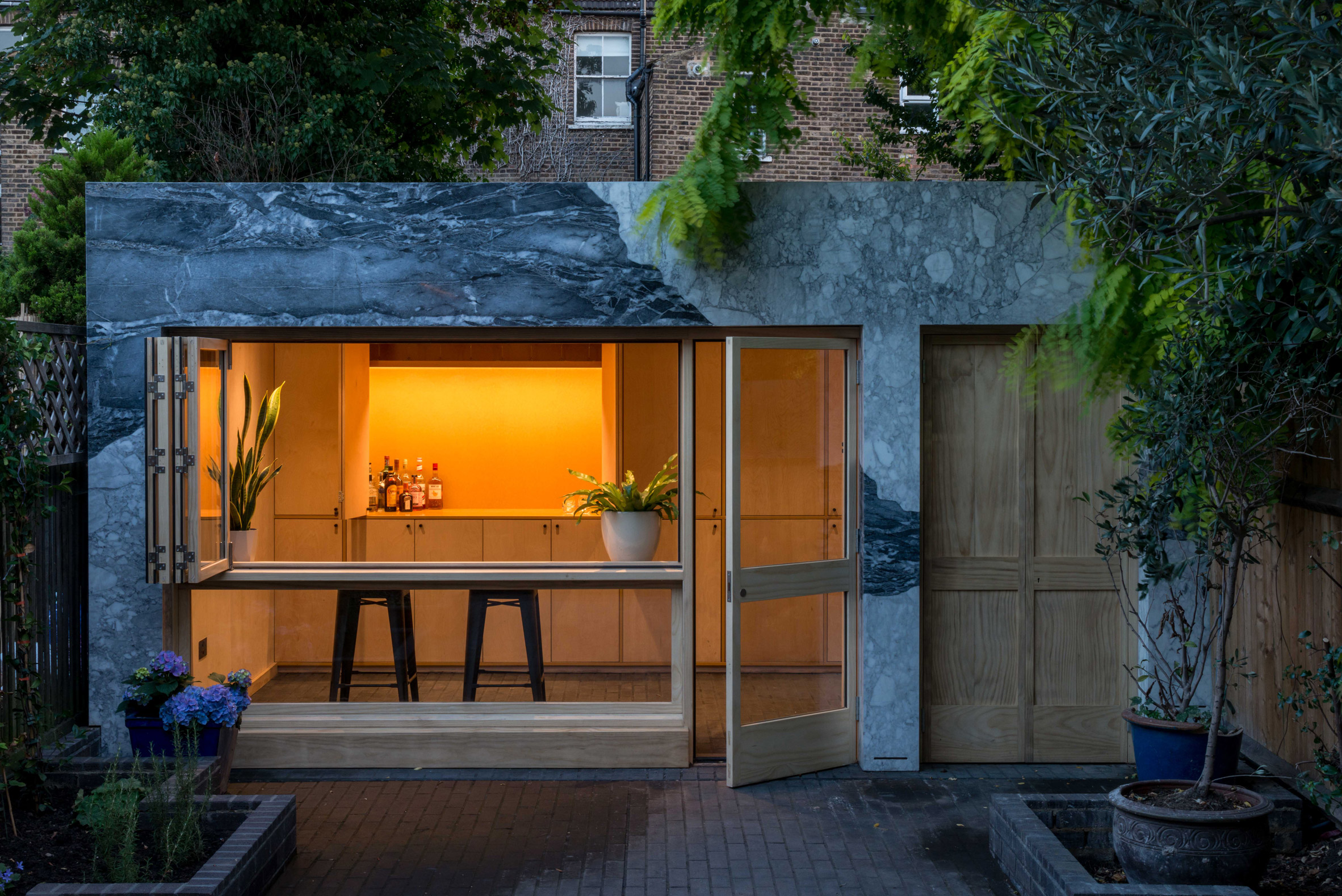 Marble-clad garden room of Hansler Road house extension by Alexander Owen Architecture at night