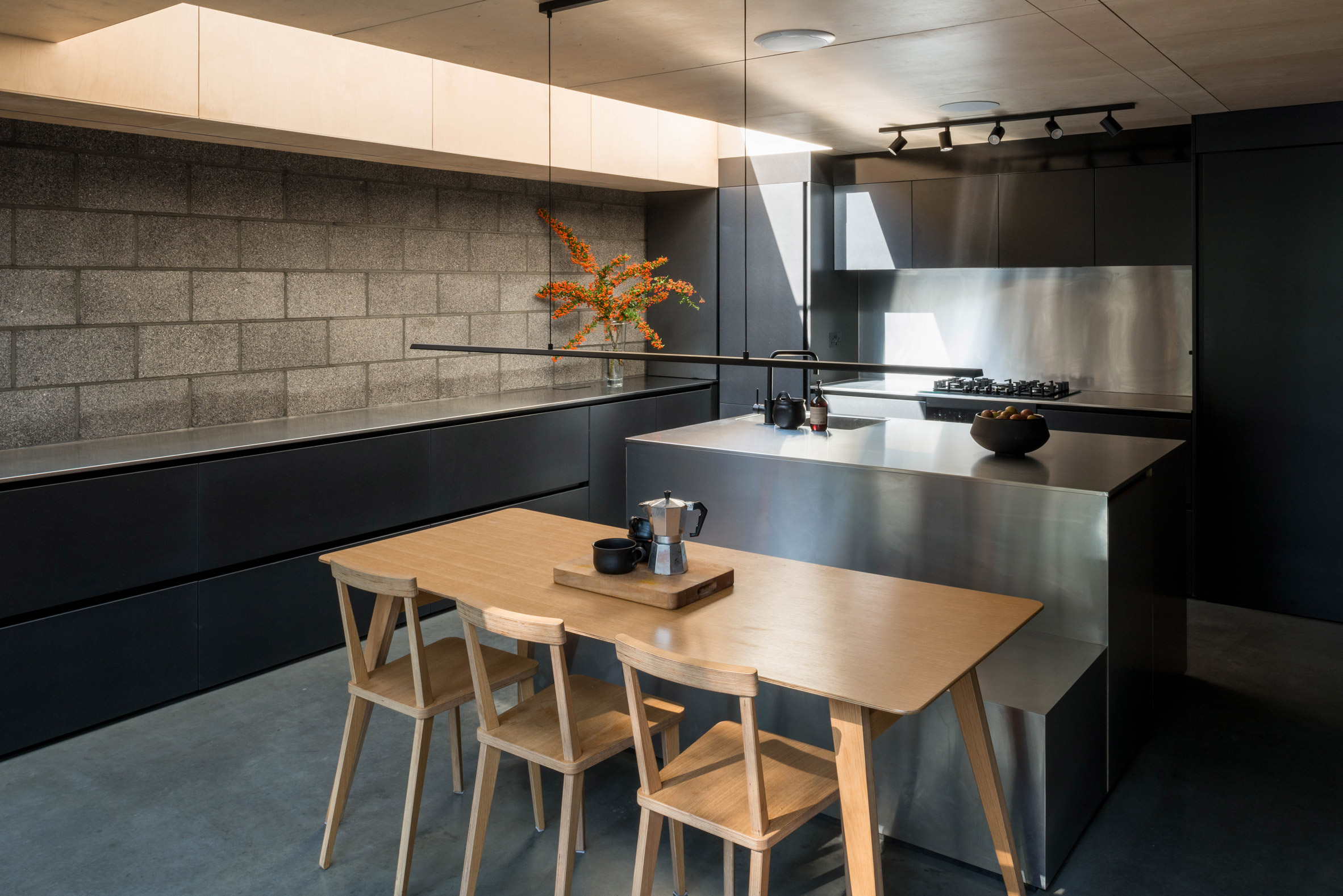 Stainless steel kitchen and pewter brick walls of Hansler Road house extension by Alexander Owen Architecture