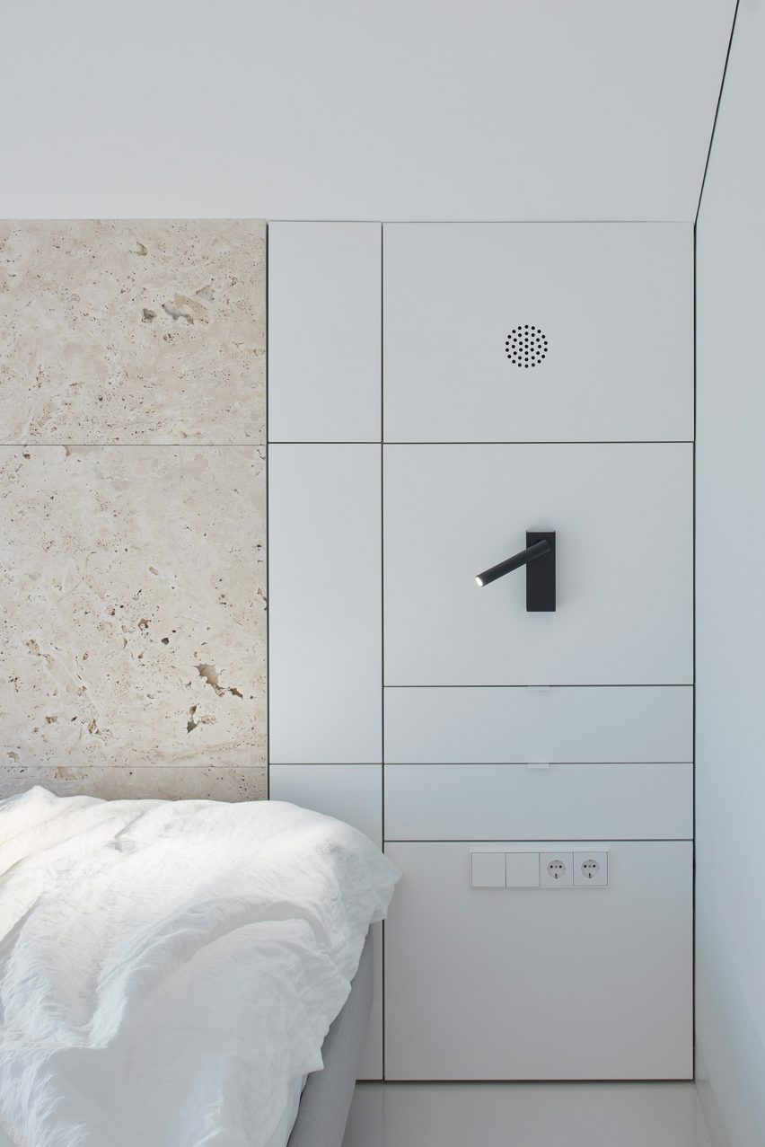 Bedroom with built-in lighting, storage and travertine wall in Greetings from Rome apartment