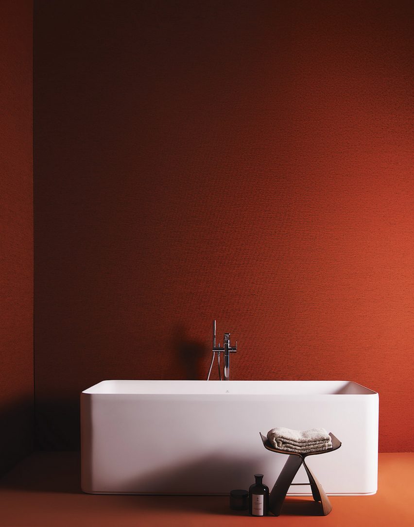 A warm orange bathroom with a freestanding white bath