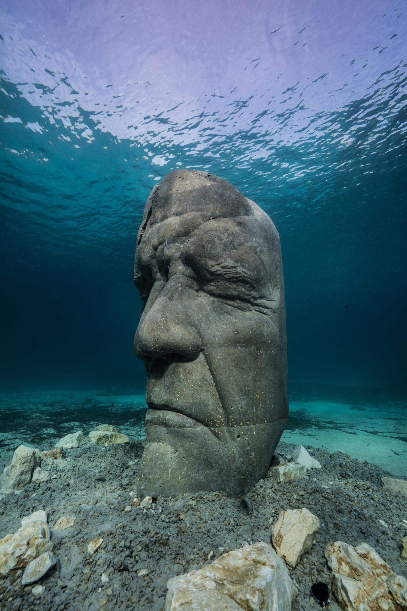 A cement sculpture of a human head under water