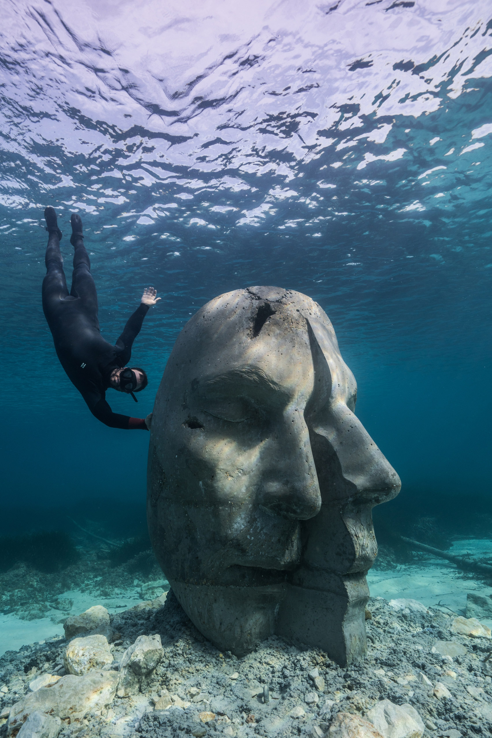 A snorkeler alongside an underwater sculpture
