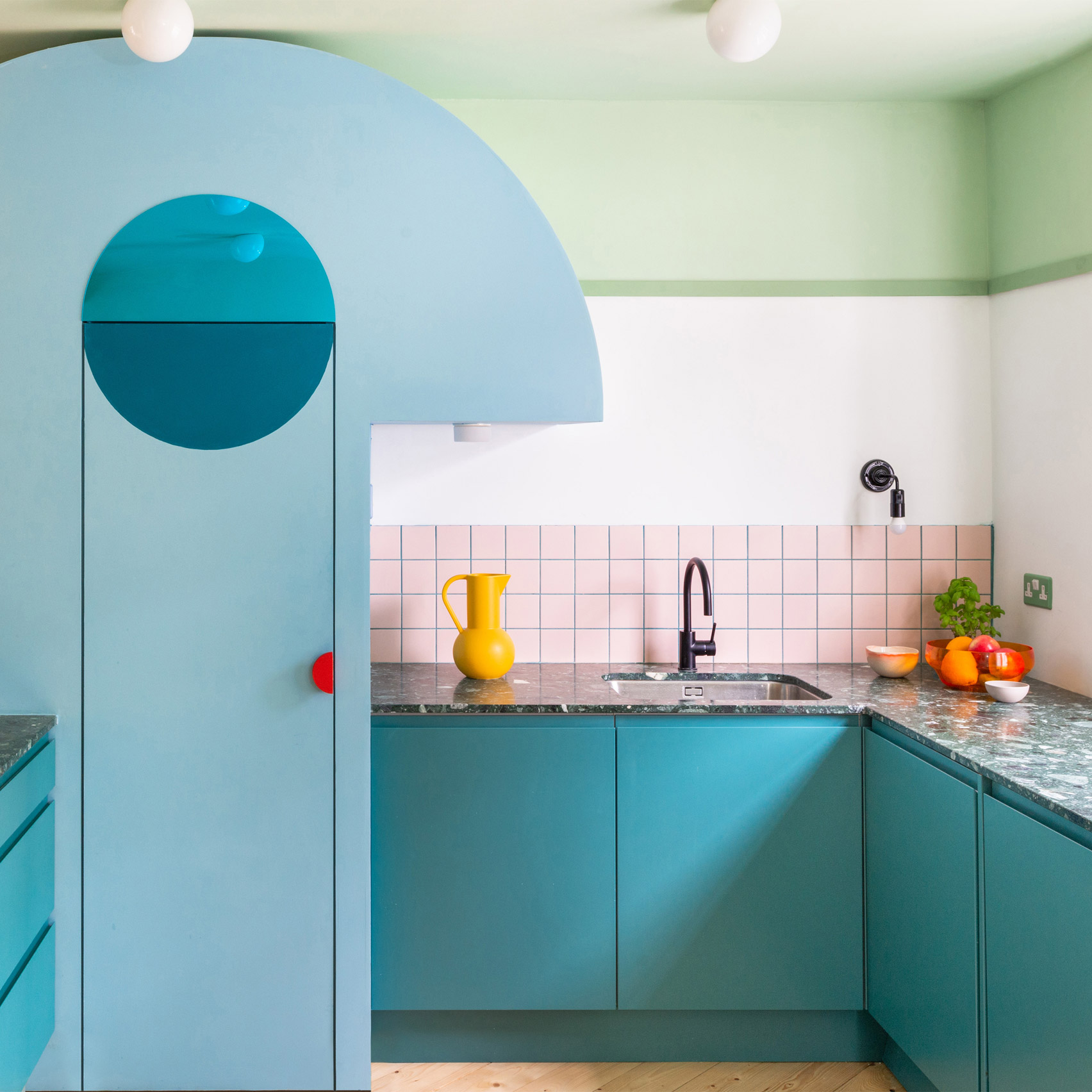 A colourful kitchen with blue cabinetry and pink tiles