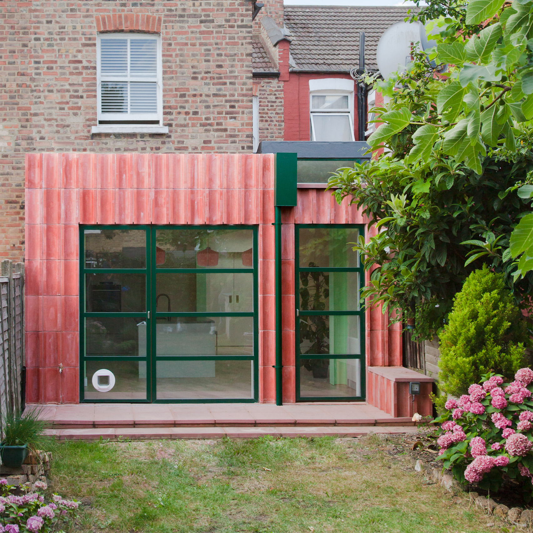 A pink-hued concrete extension with green detailing