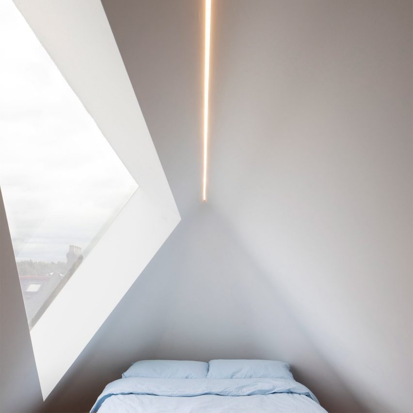 An angular white-walled bedroom with a skylight