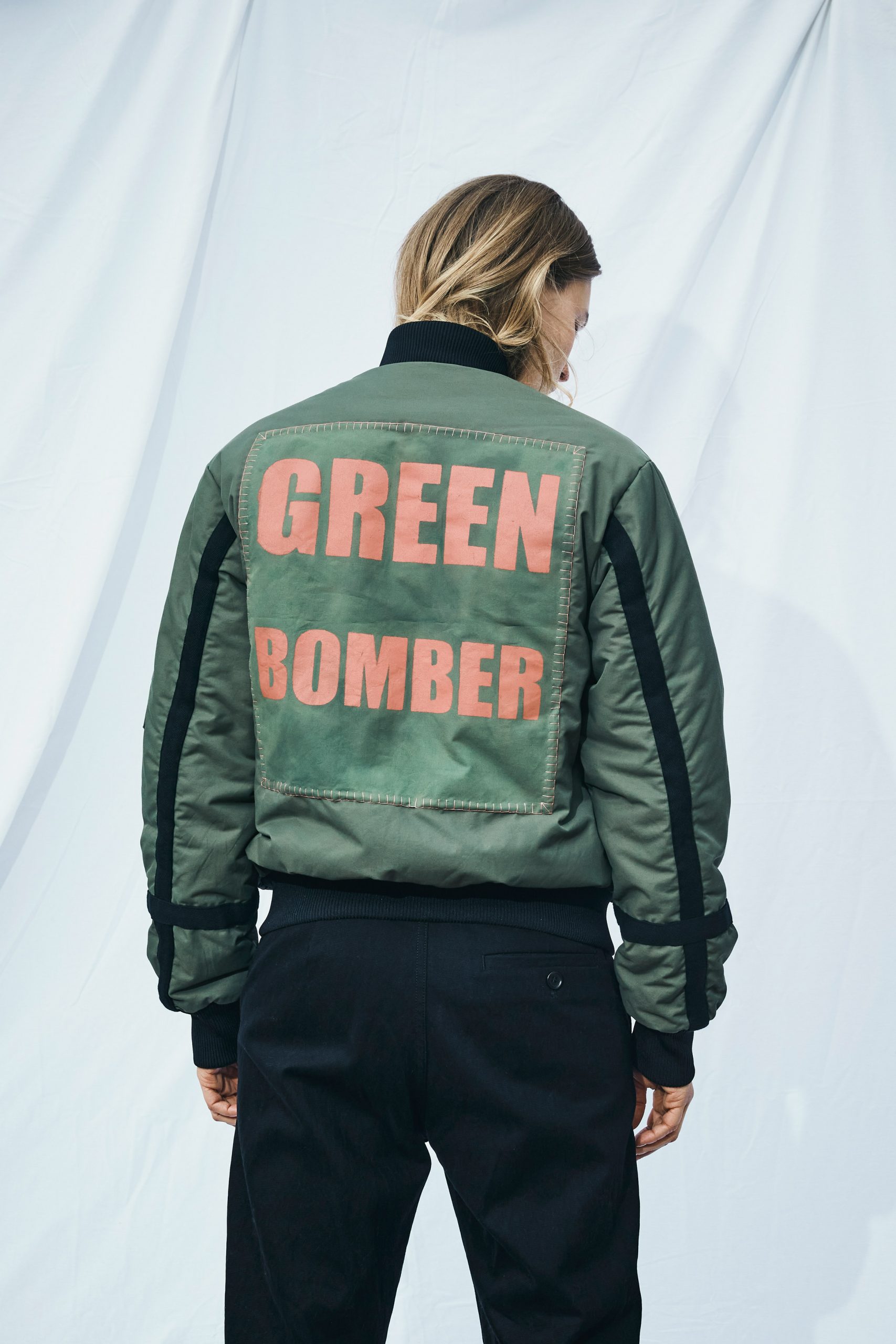 Green bomber jacket with photosynthetic applique and slogan print