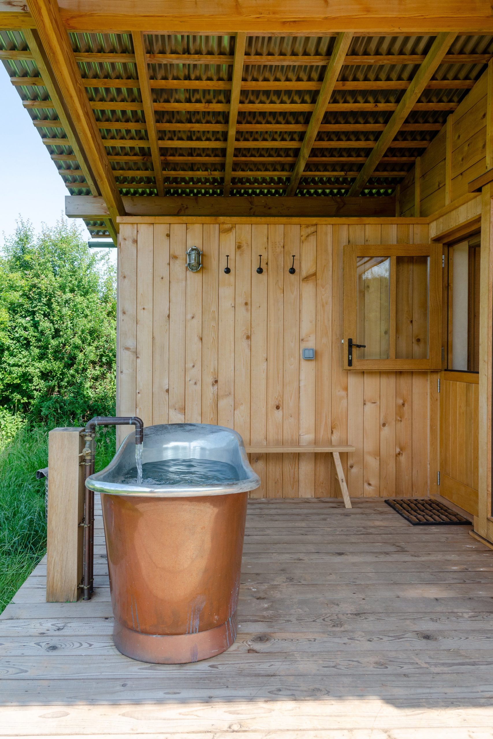 A cabin terrace with a freestanding copper bathtub