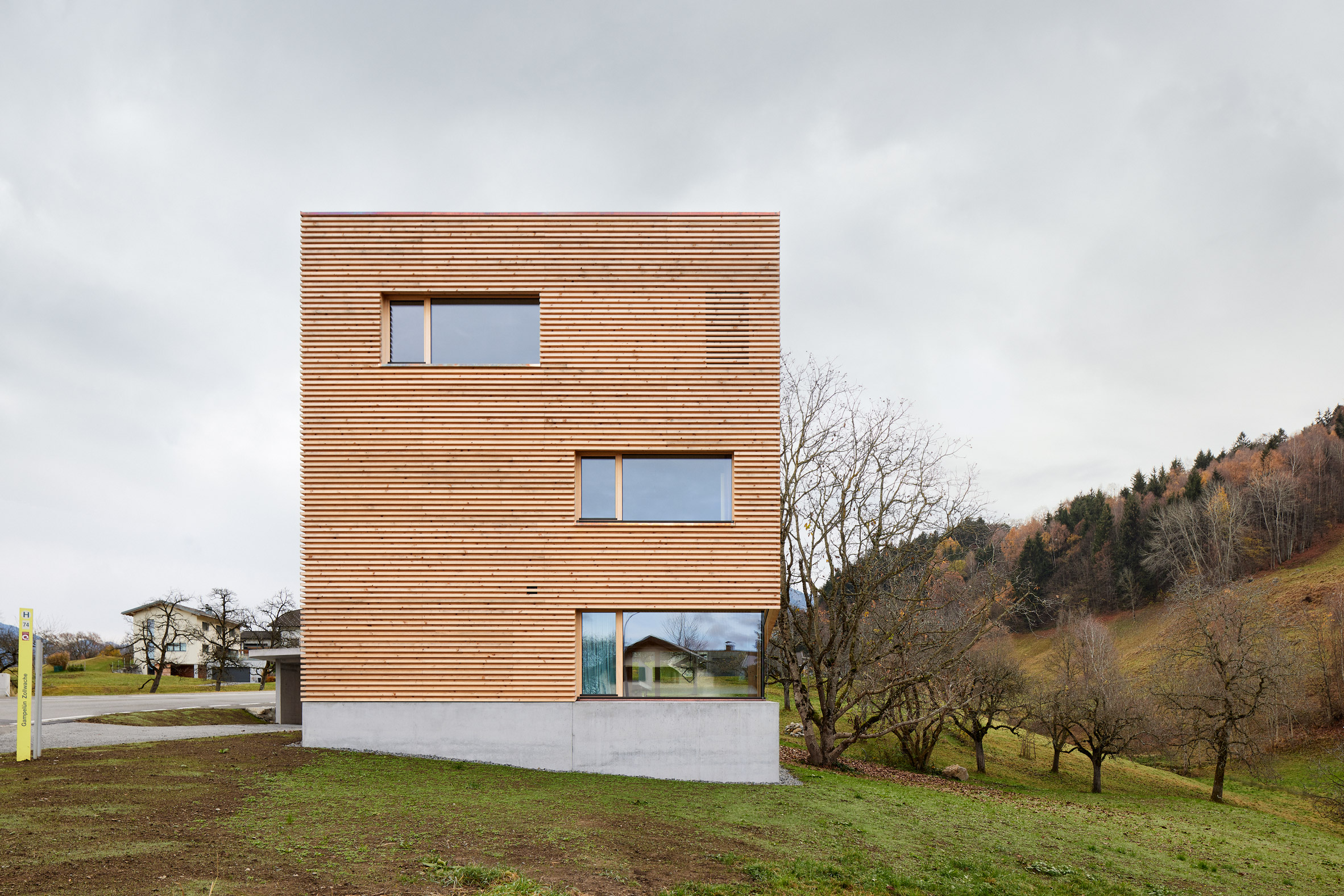 A square timber-clad house with a concrete base