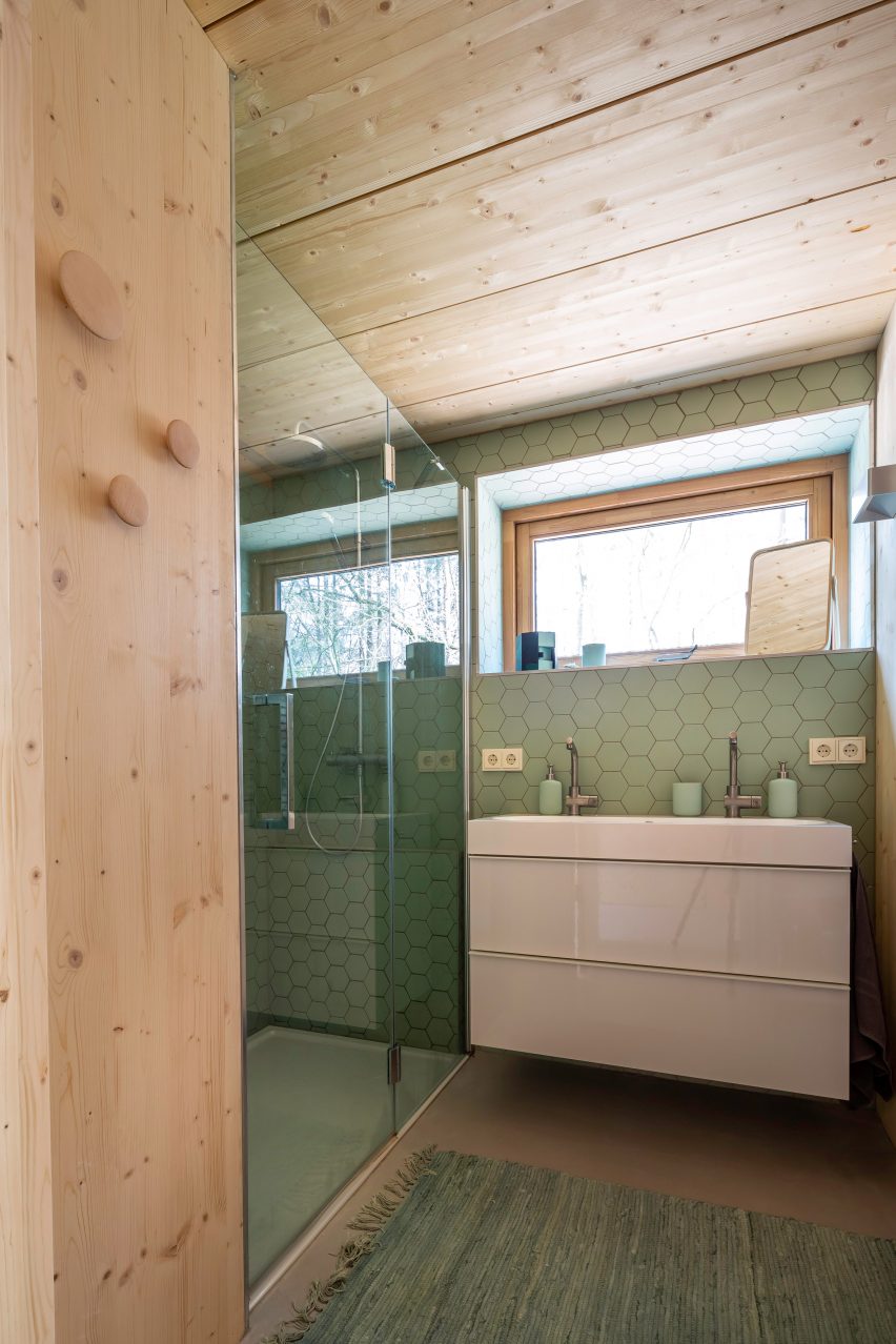 A wooden bathroom with green tiles
