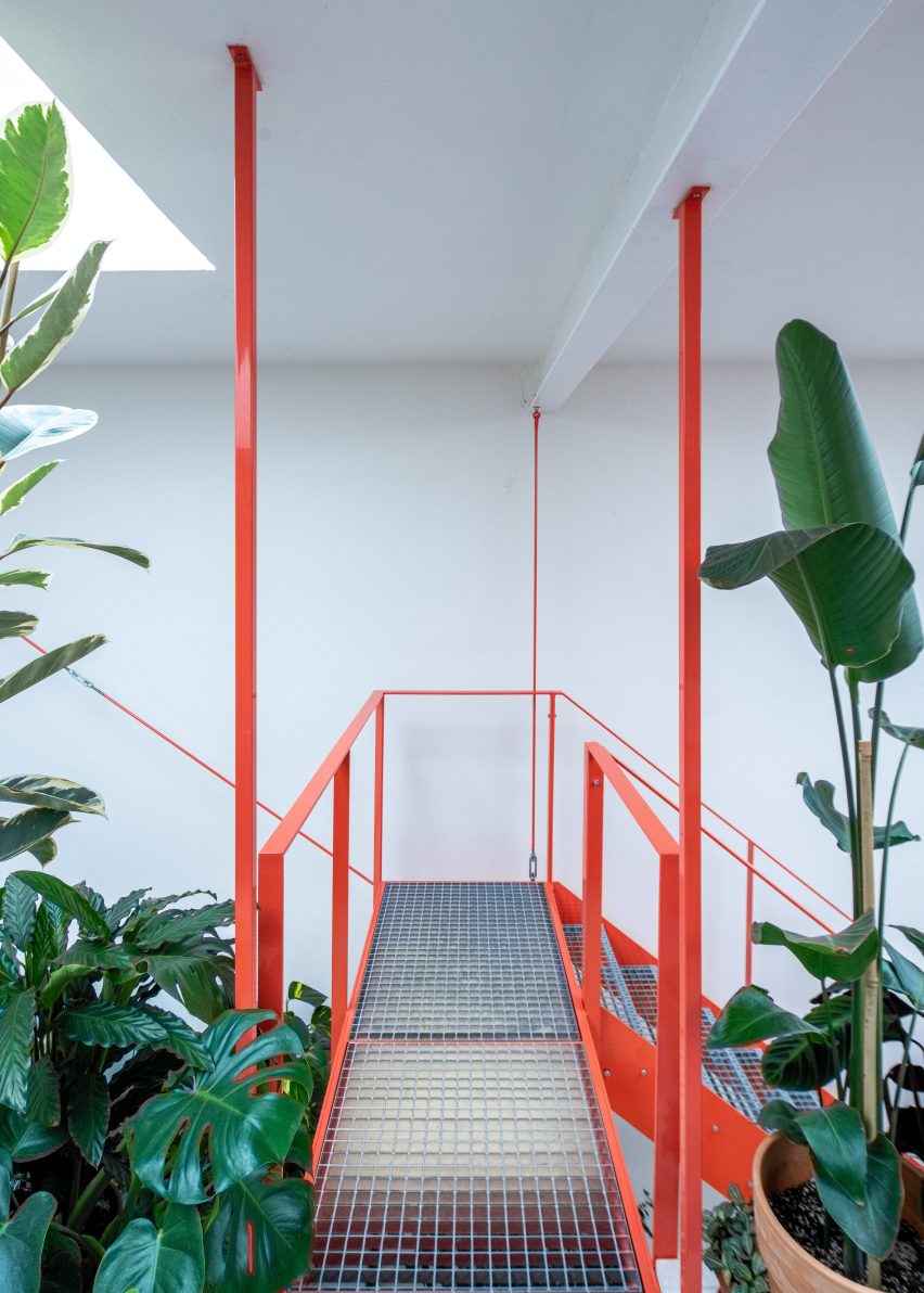 Metal tangerine stairs and plants in cafe designed by Kogaa