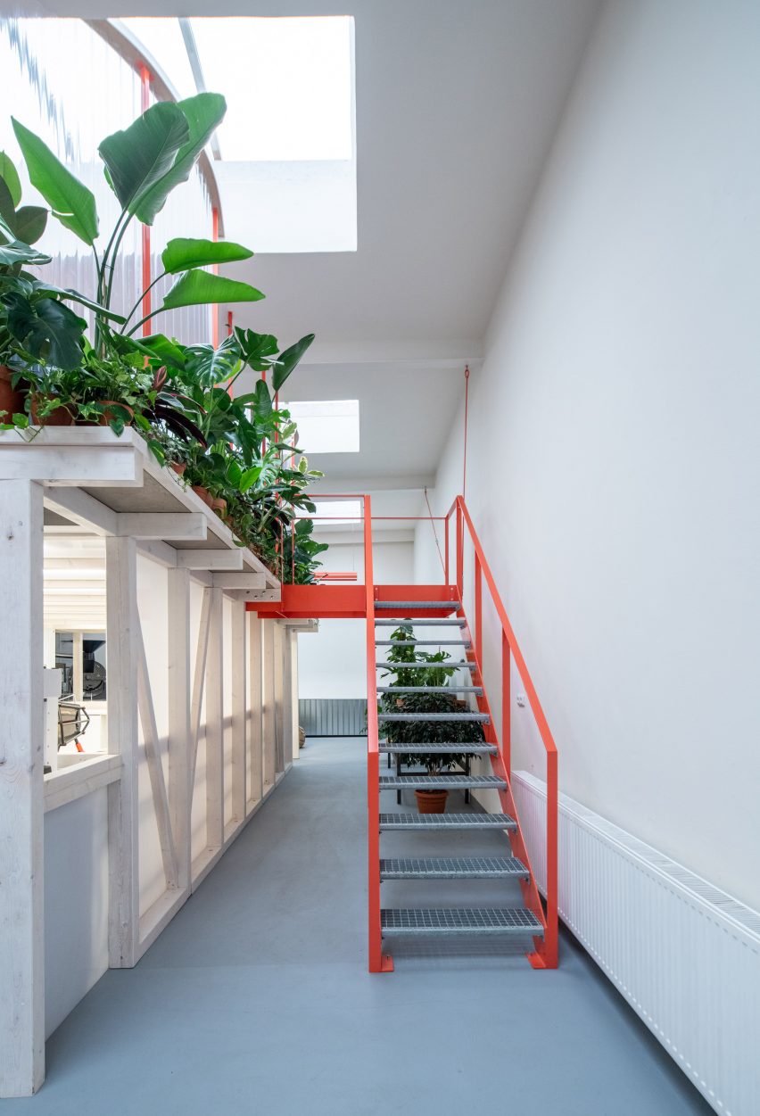 Tangerine-coloured stairs leading up to mezzanine in cafe by Kogaa