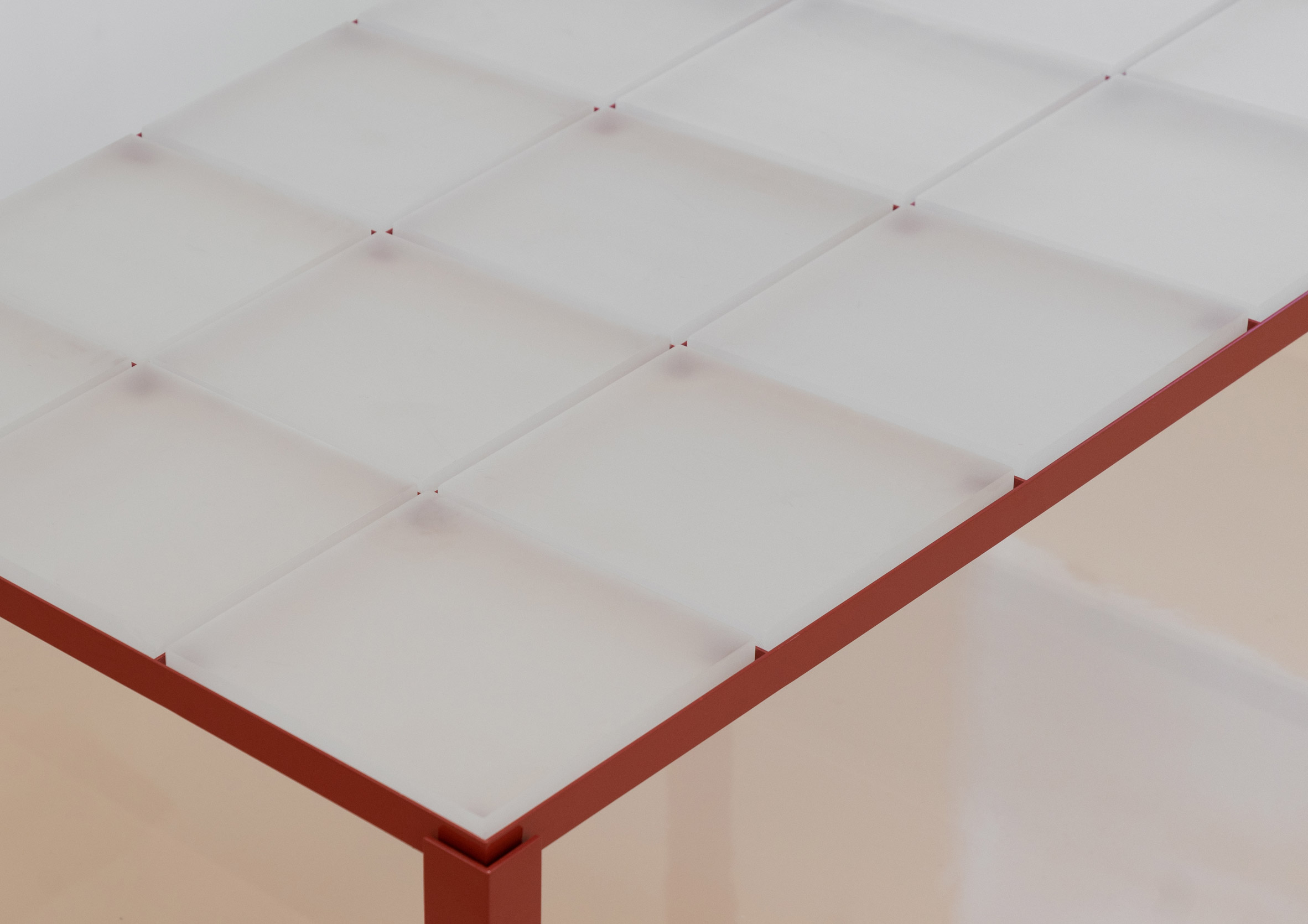 Red steel table inlaid with square resin tiles from store interior by Say Architects