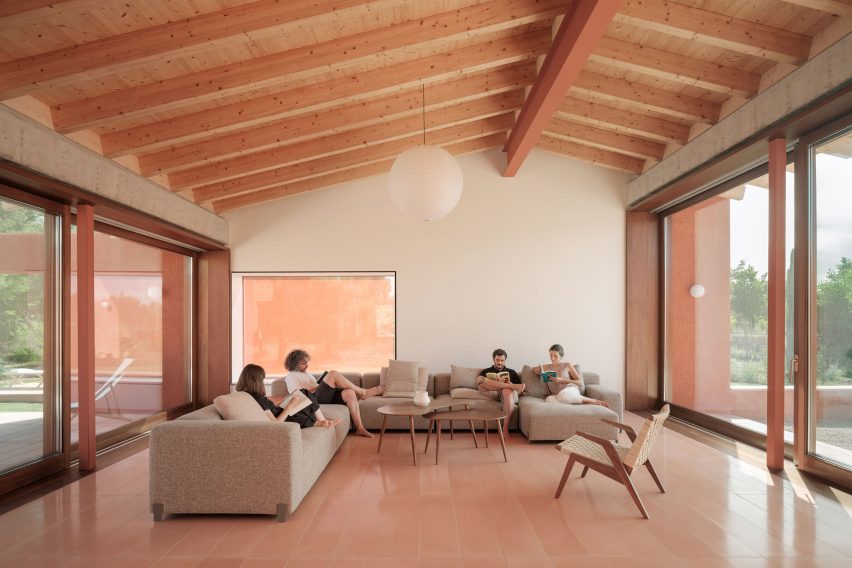A living room with an exposed wood ceiling and pink floor tiles