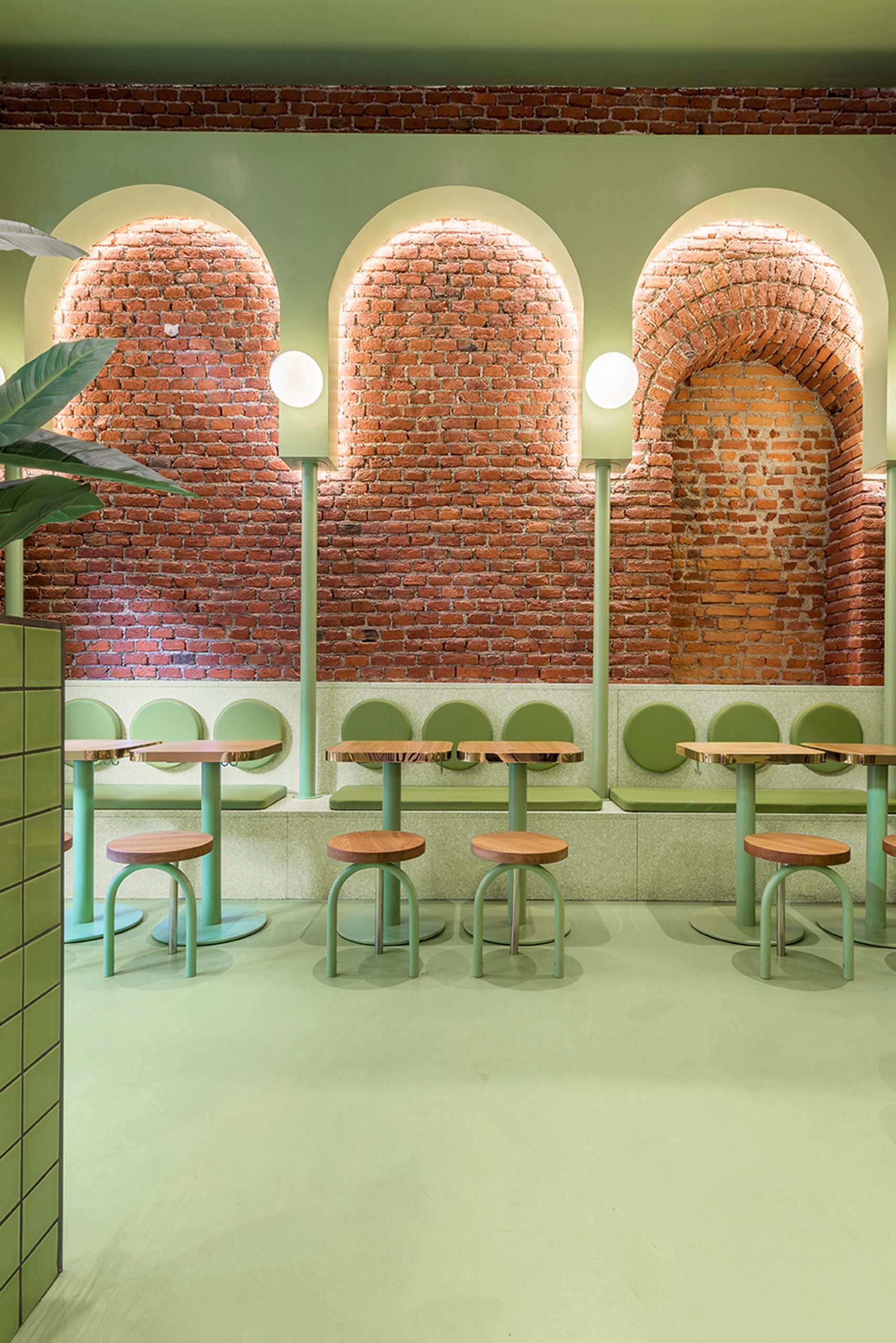 Green arches and exposed brick in seating area of Bun restaurant by Masquespacio