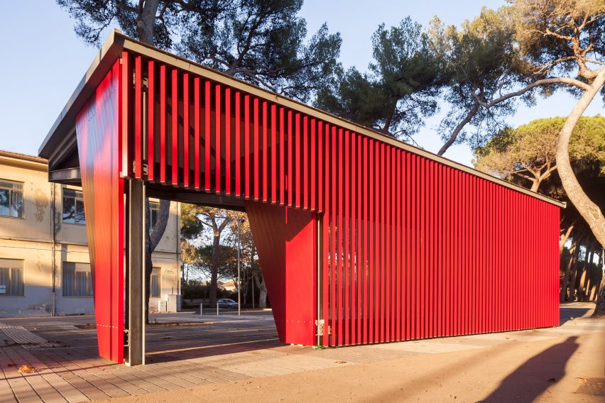 A red bus stop made from aluminium slats