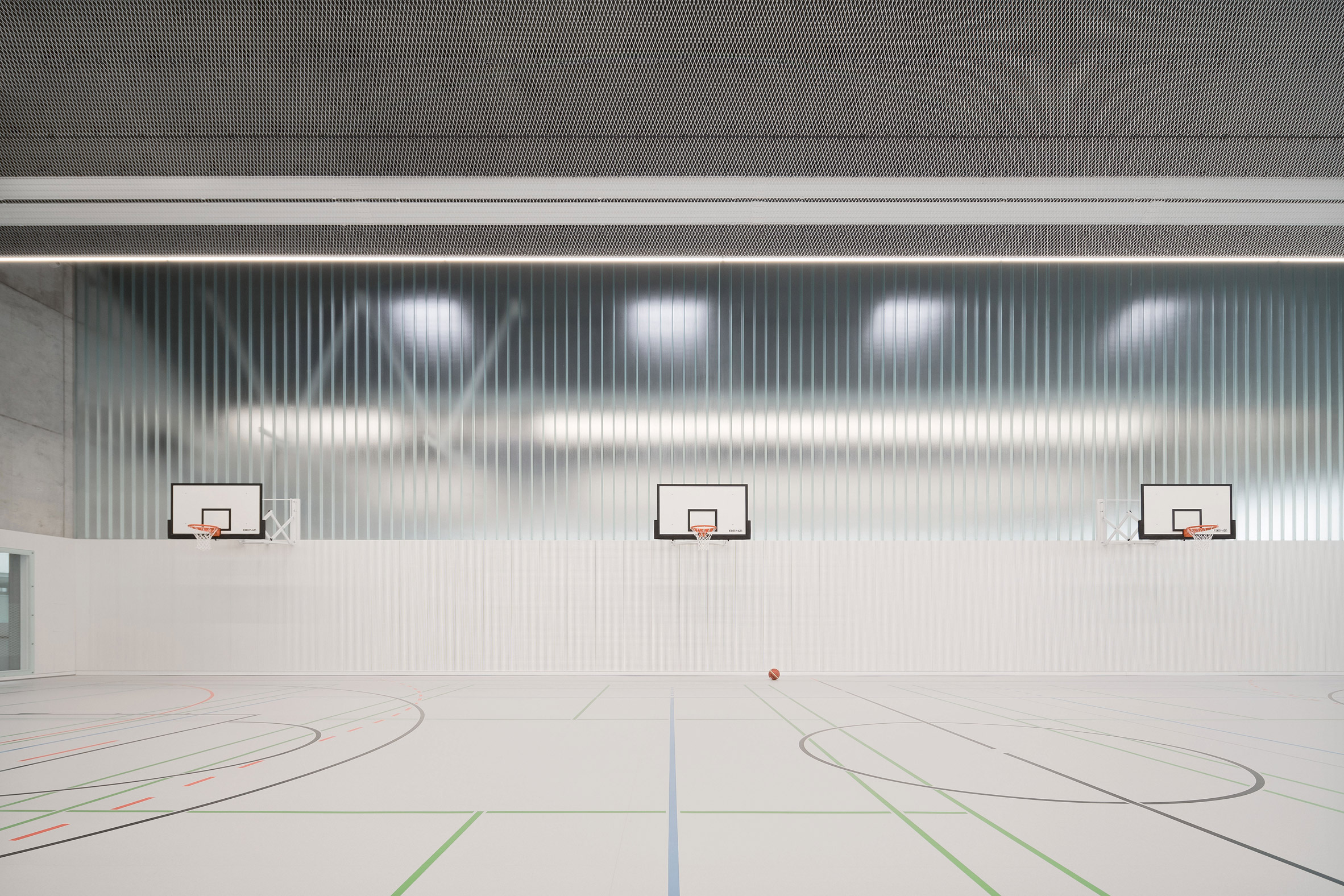 Basketball hoops are organised against a partially glazed wall