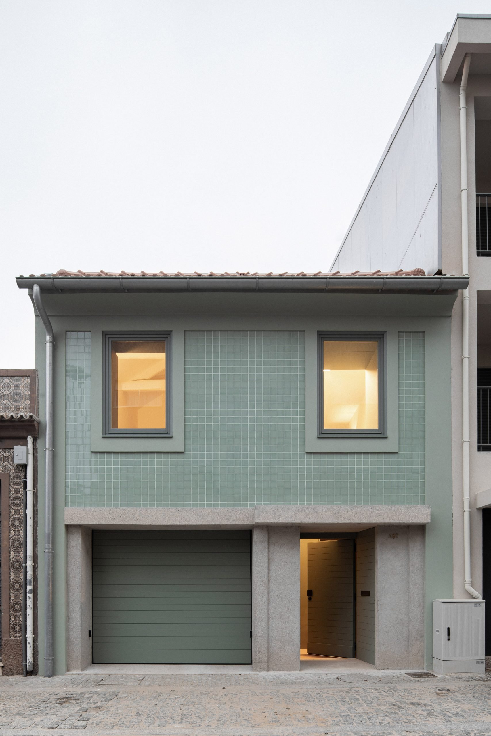 The facade has a concrete and tile material palette by depA Architects