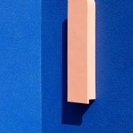 A bright blue wall and pink outdoor light