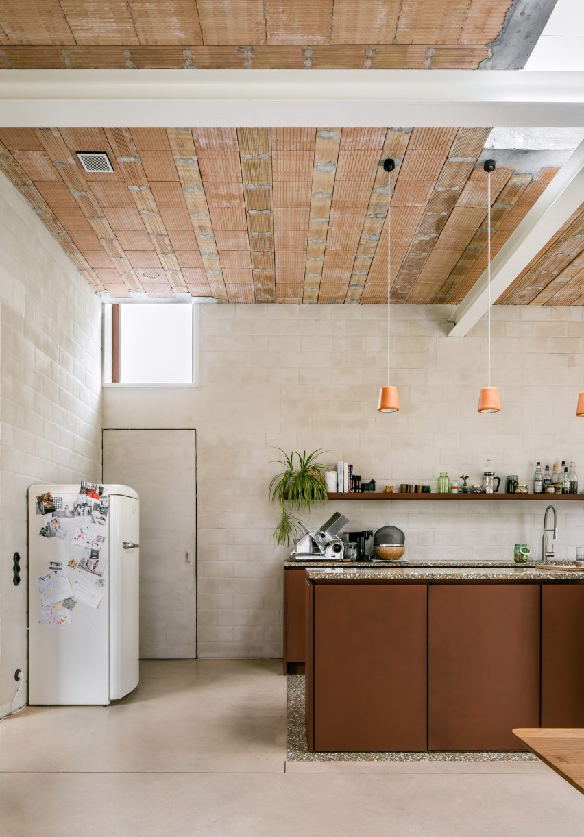 A kitchen with a tall ceiling and rough plaster walls