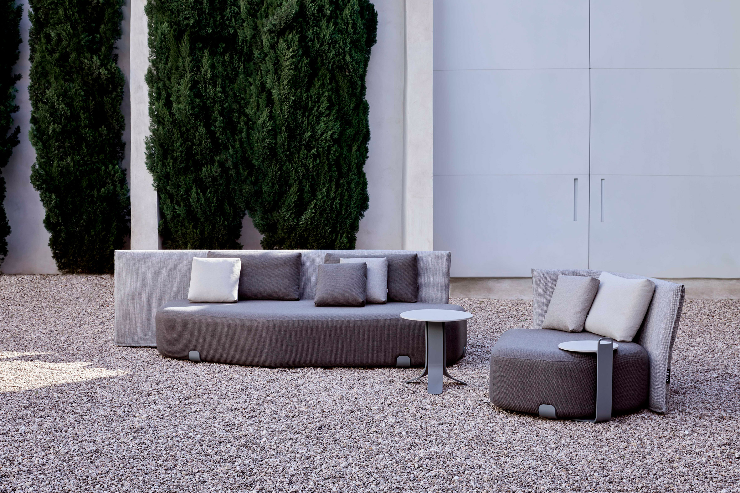 There is a grey upholstered outdoor seating by Gan