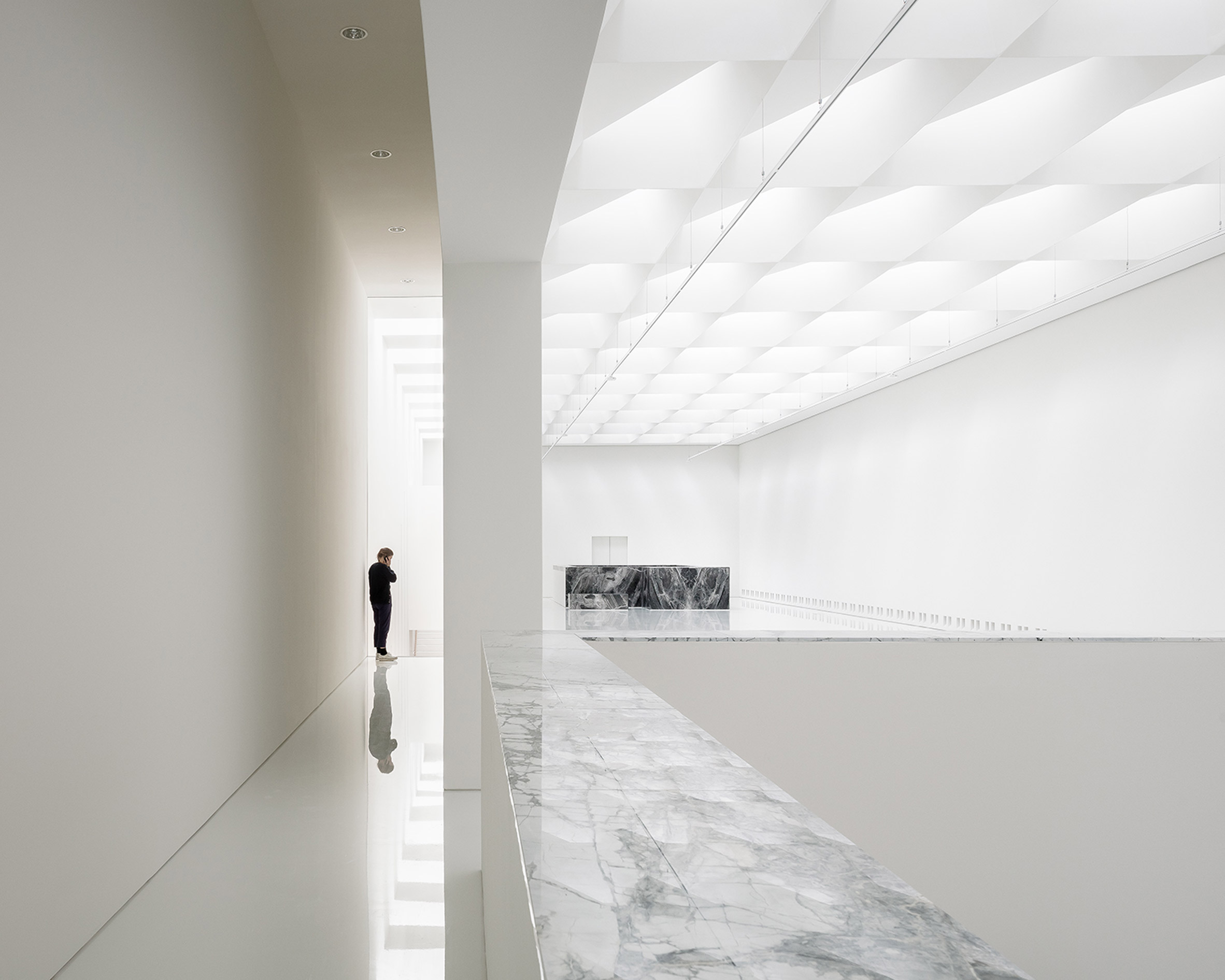 Exhibition hall in modern museum extension by Kaan Architecten with white glossy floors and marble detailing