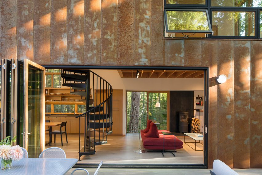 The Corten-steel house is nestled within a forest