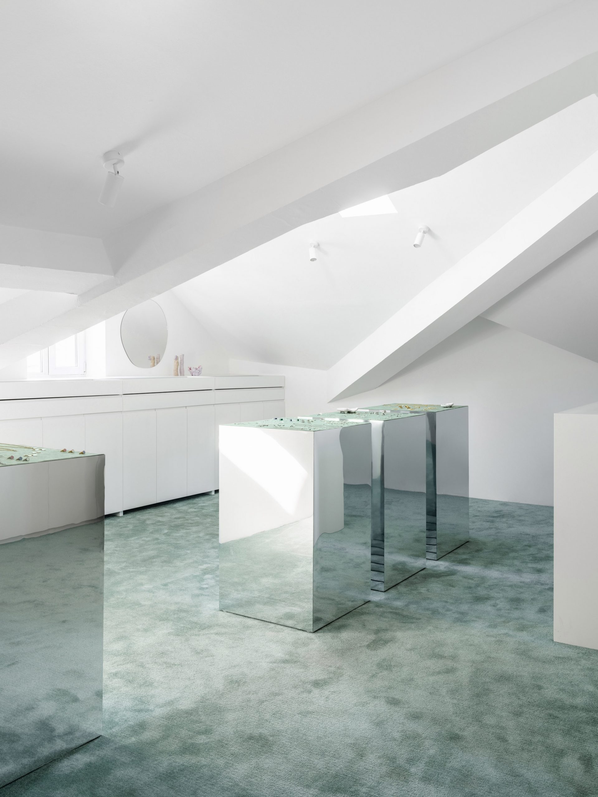 Sea-green carpet and mirrored display plinths in Qari Qris and Moonswoon showroom interior