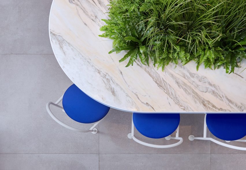 Communal marble table with central plant pot in tea shop by Raams Architecture Studio