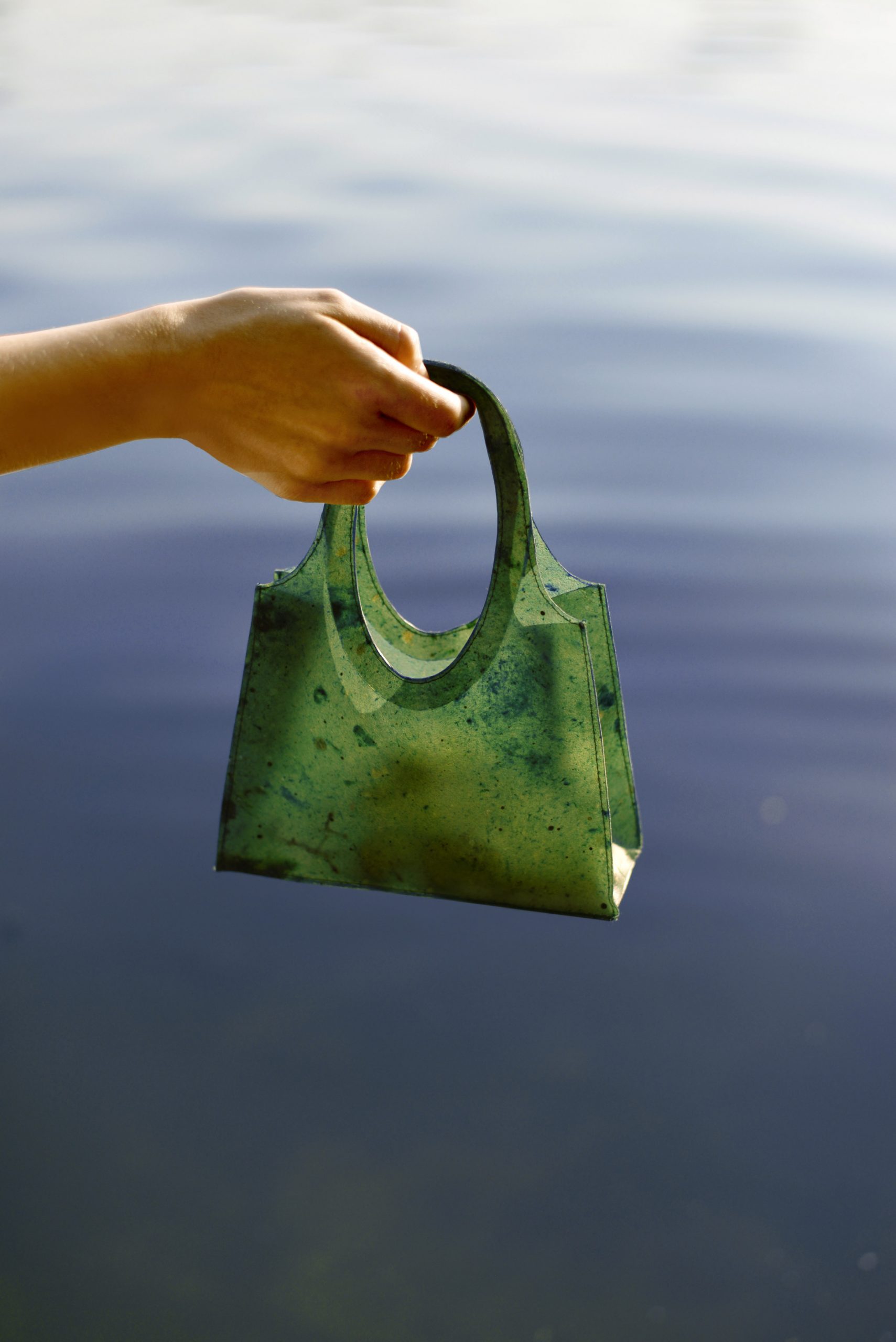 Green Sonnet155 carrier bag being dangled over water
