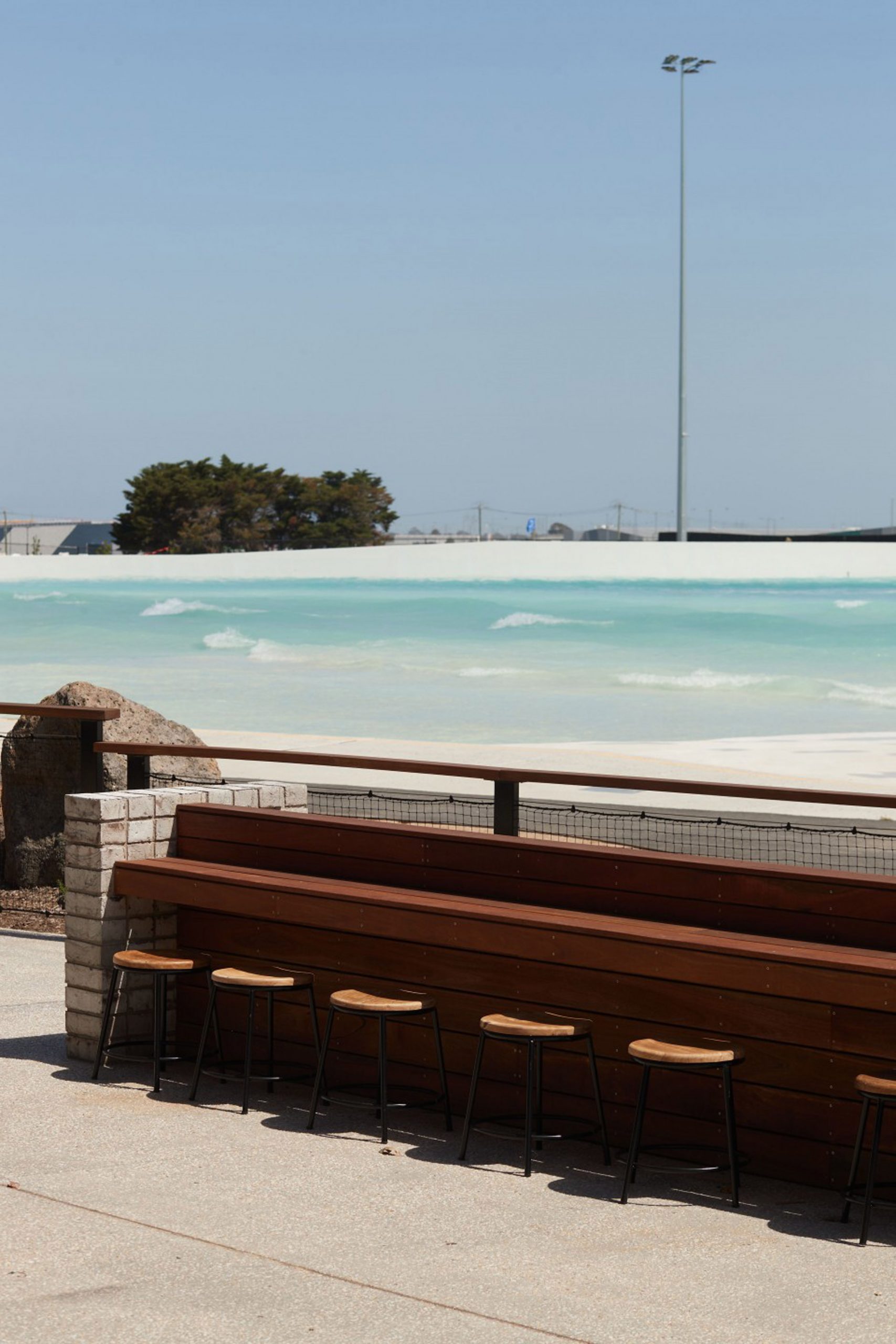 Wooden seating area overlooking wave pool in Melbourne Urbnsurf