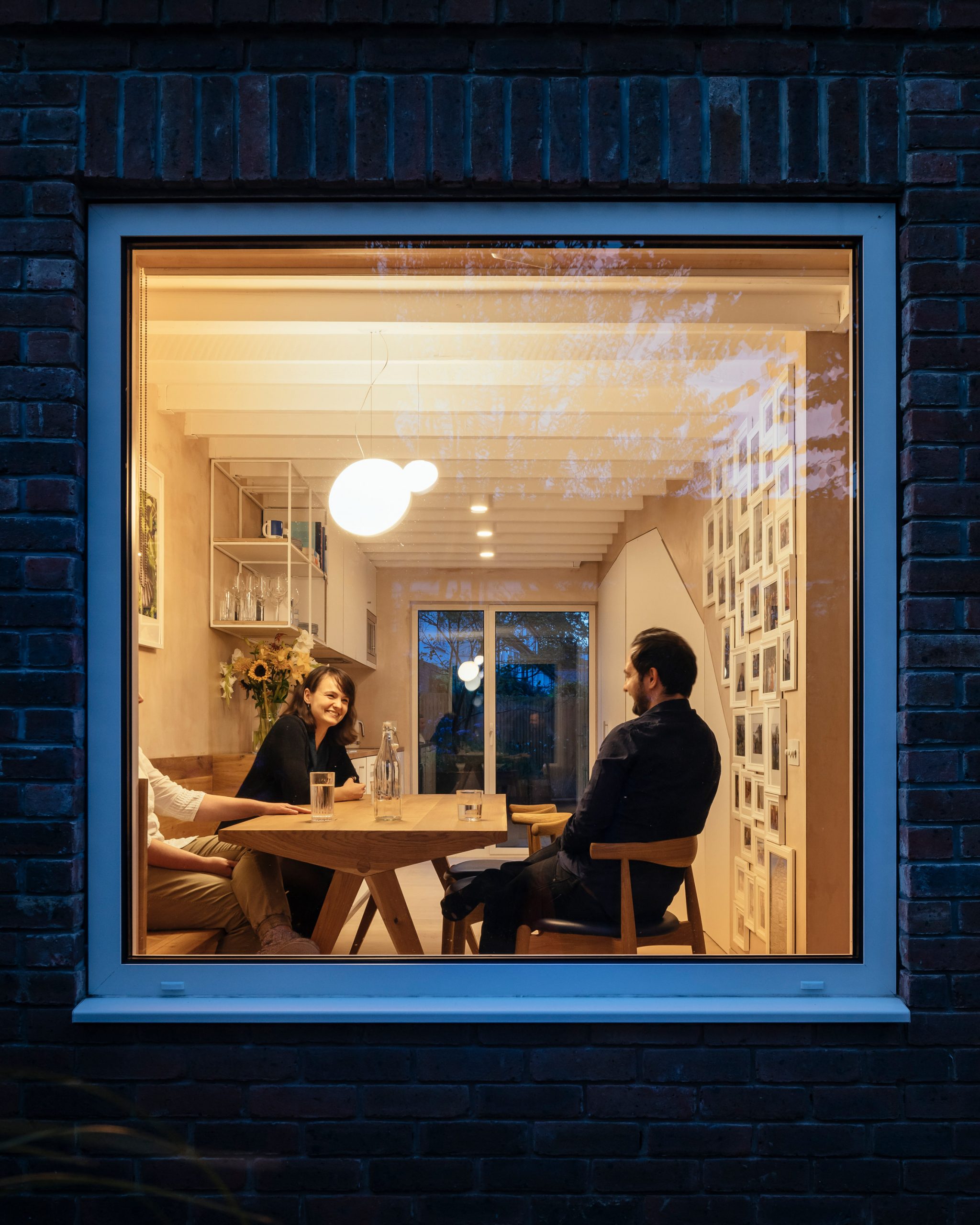 Large square window looking into house with people dining