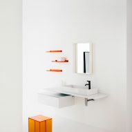 A white bathroom with orange accessories