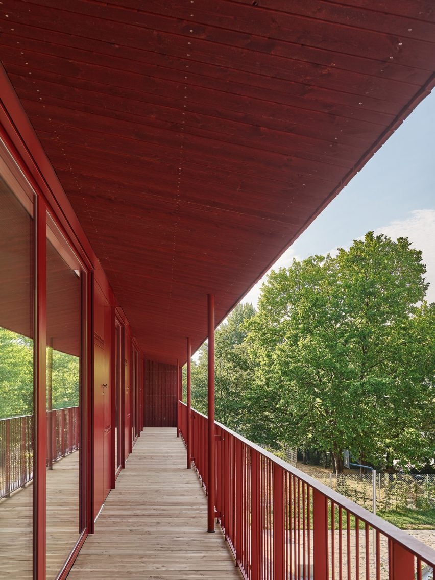 Red railings line the balcony terrace of daycare centre by Birk Heilmeyer und Frenzel Architekten