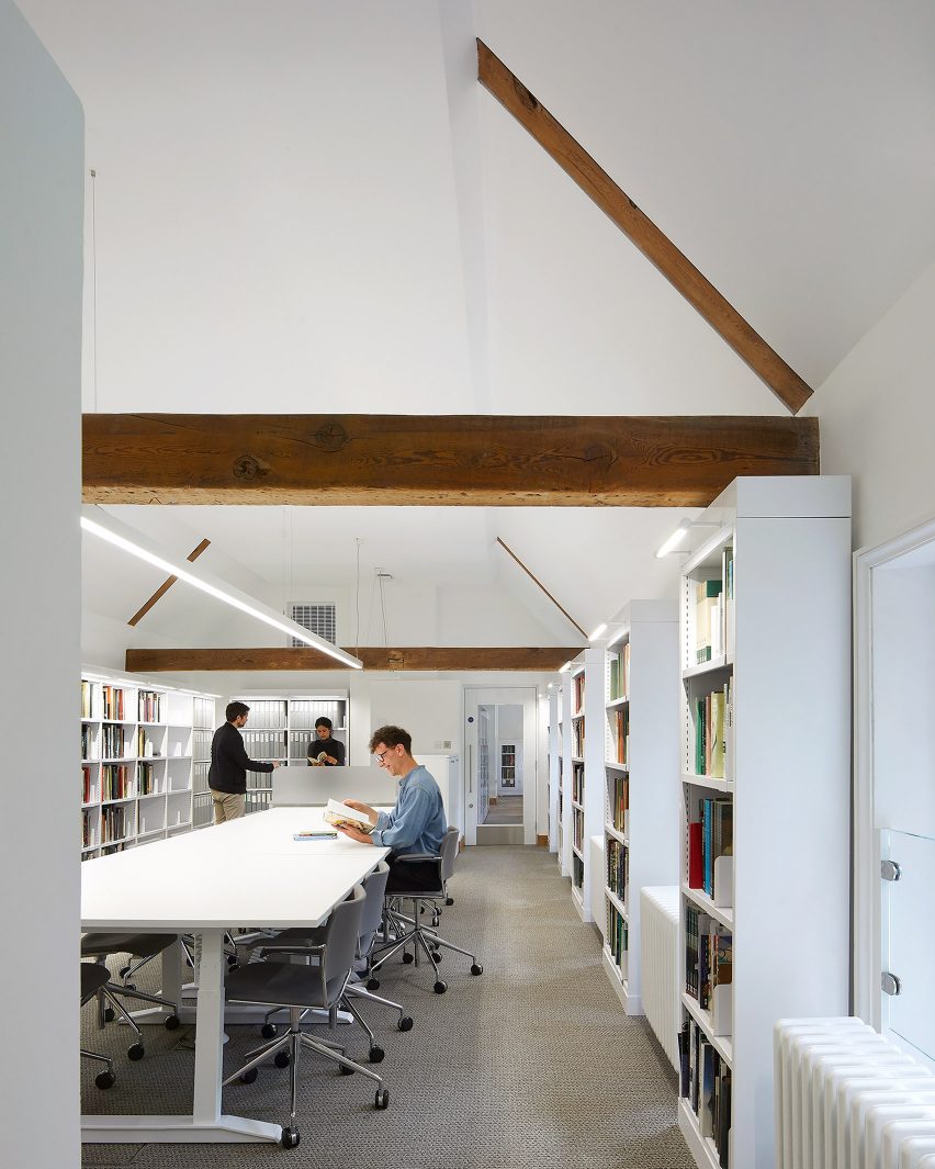 Perpustakaan berdinding putih dengan balok kayu ekspos