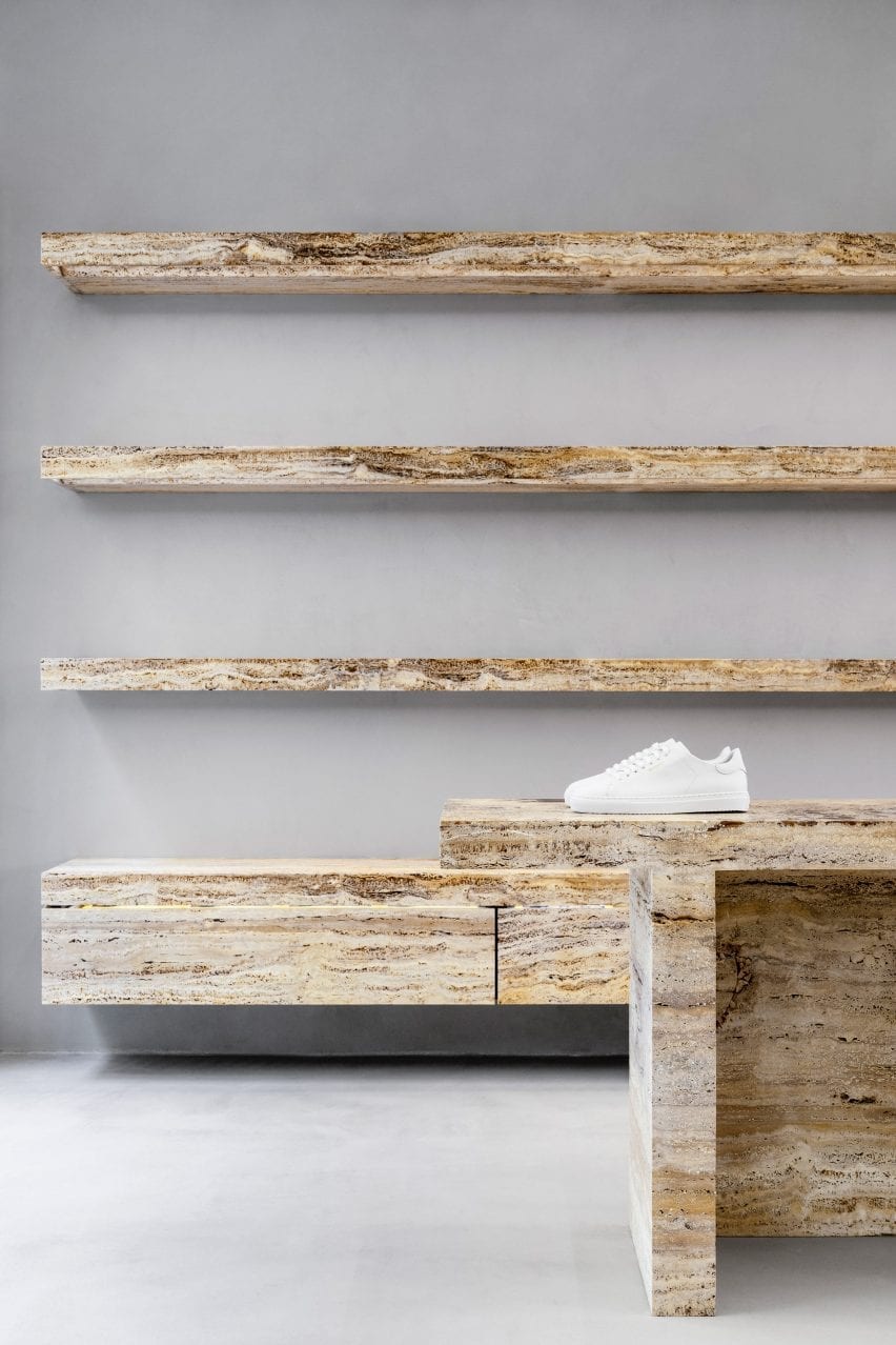 White sneaker on travertine shelves in retail interior by Halleroed