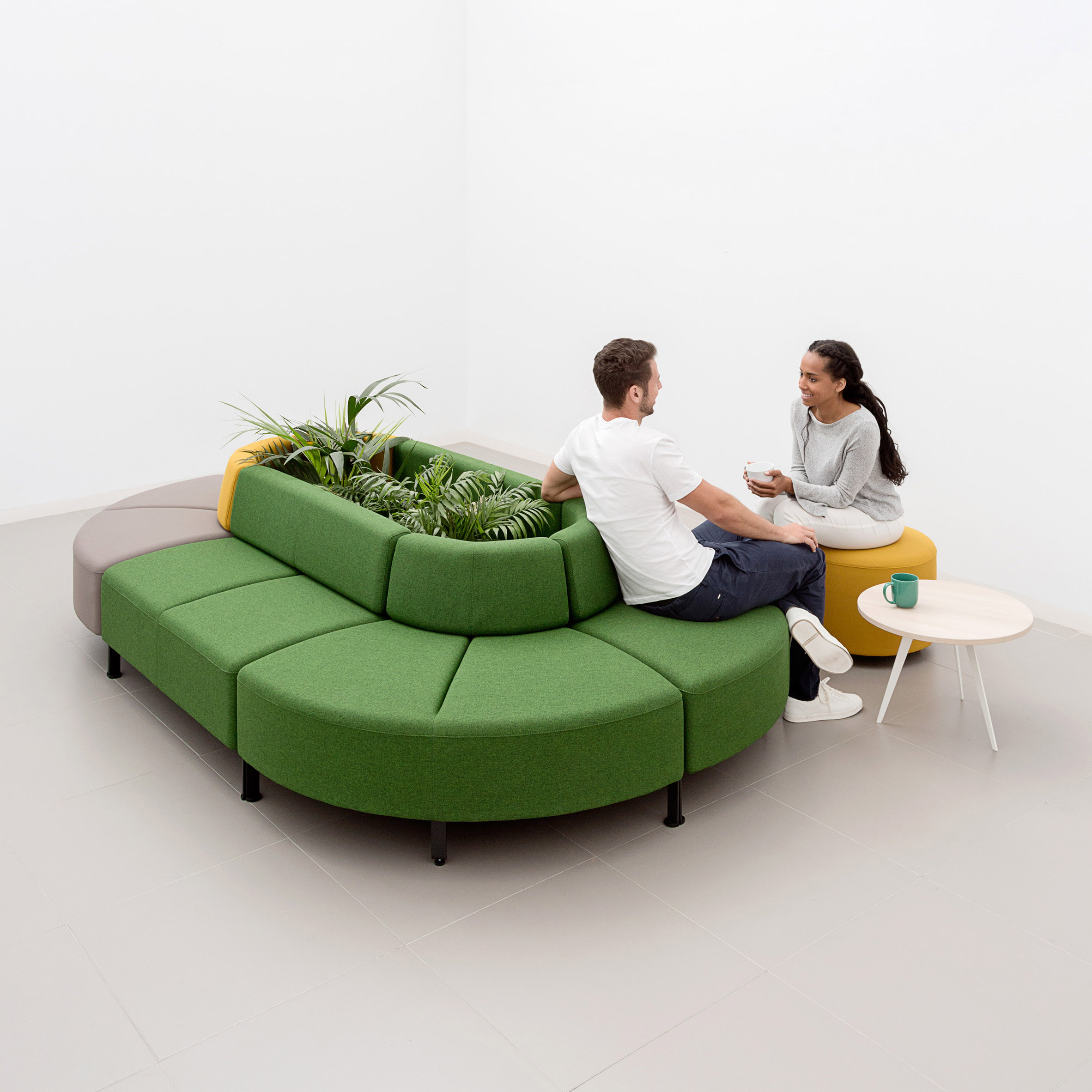 An oval-shaped sofa with a central planter by Actiu