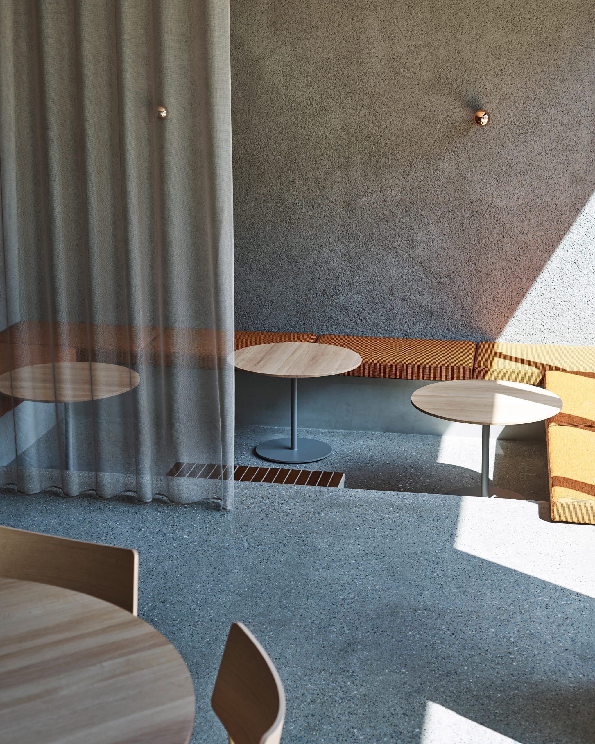 Sunken seating area with orange pillows in coffee shop by Keiji Ashizawa Design