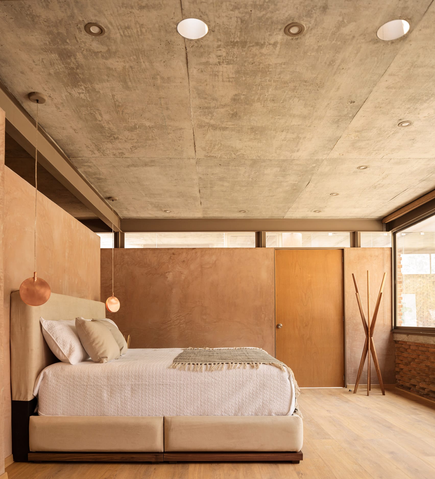 Bedroom of house in Mexico with pigmented concrete walls