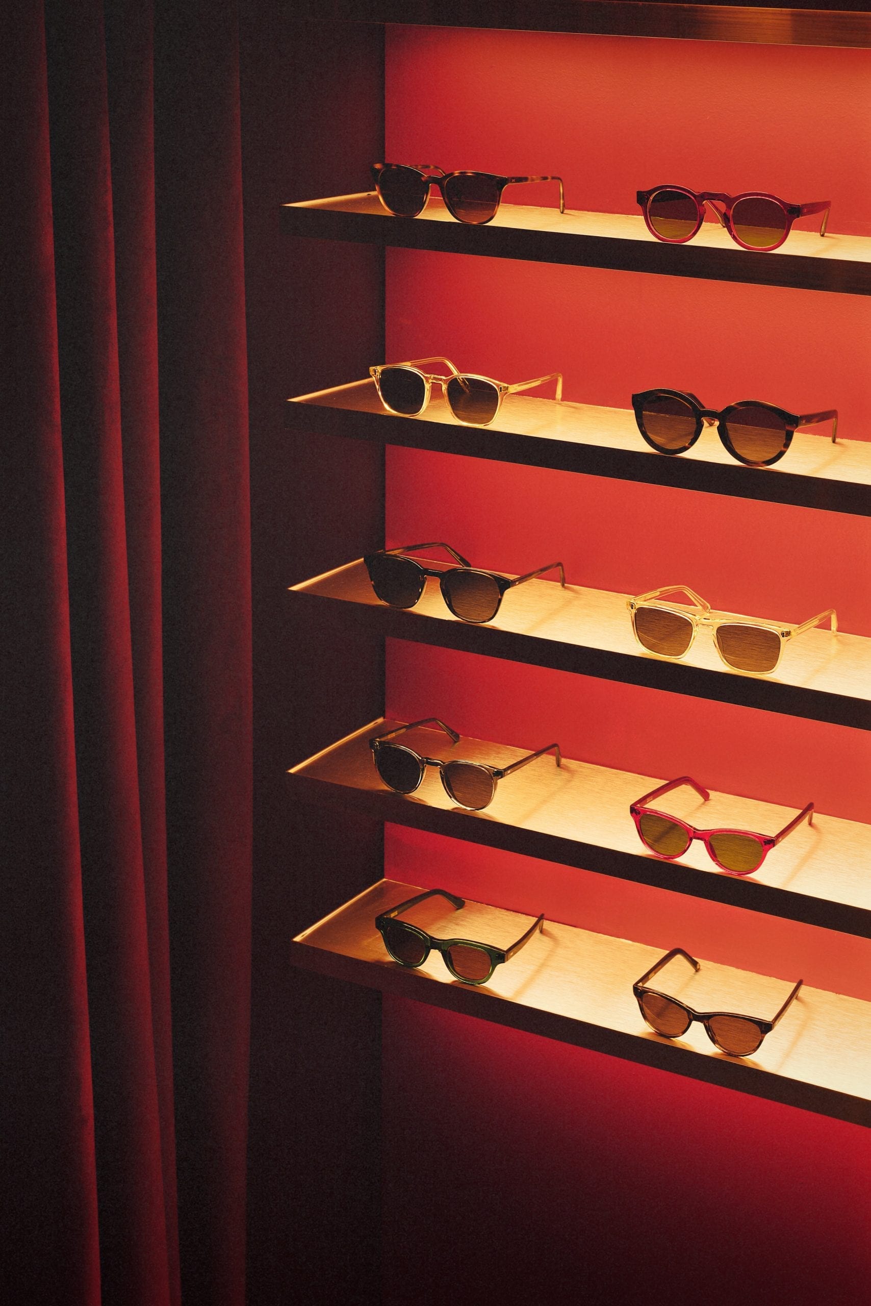 Acryclic glasses display with red velvet curtain in eyewear store by Child Studio