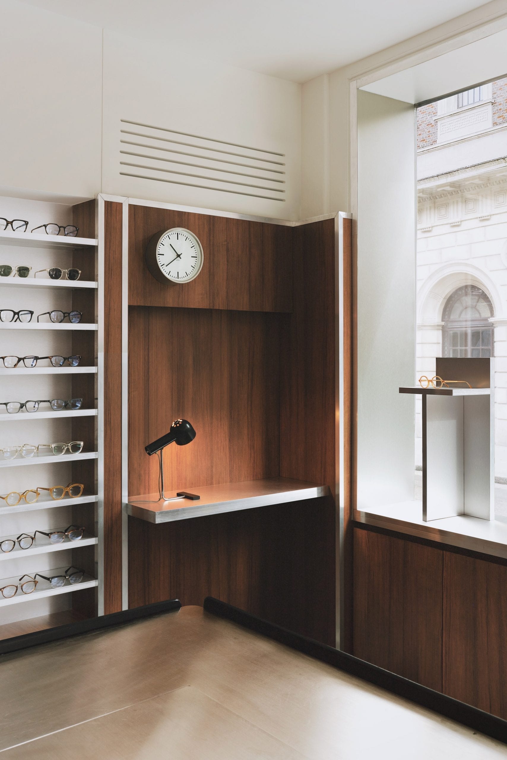 Desk nook with clock and glasses display in eyewear store by Child Studio
