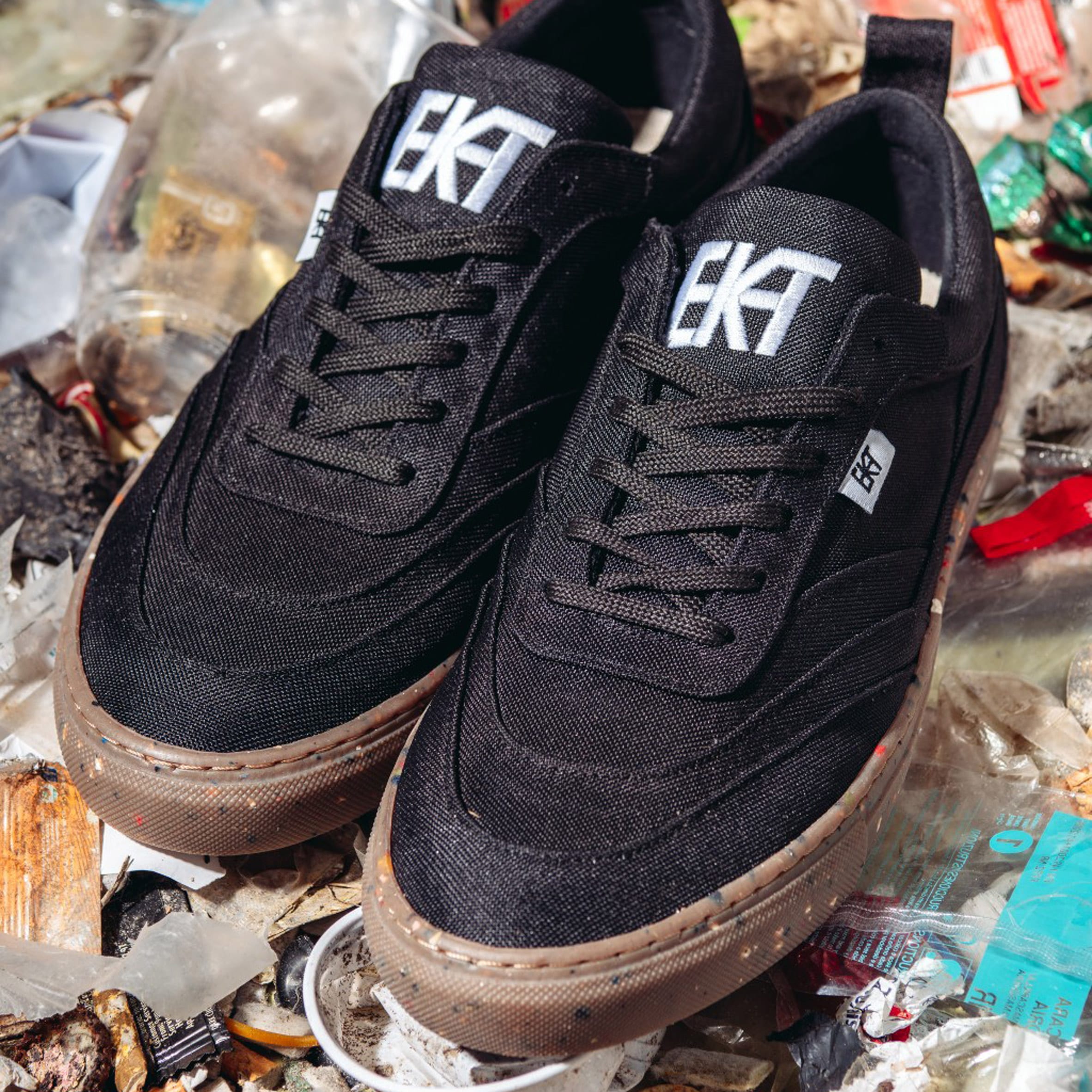 A pair of black trainers photographed on rubbish