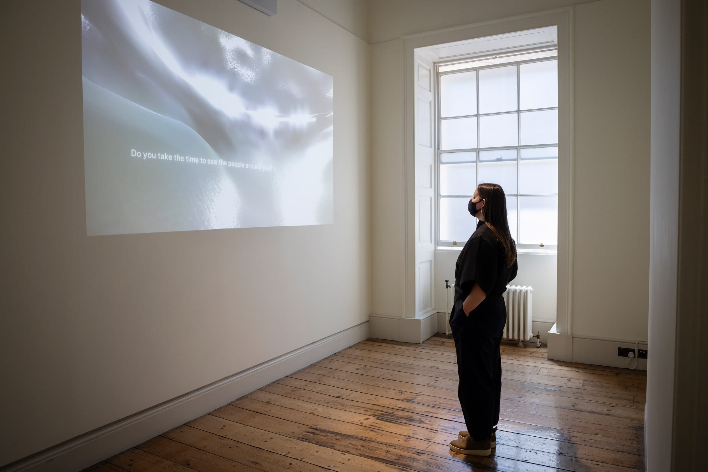 The artist is pictured watching a projection on a wall