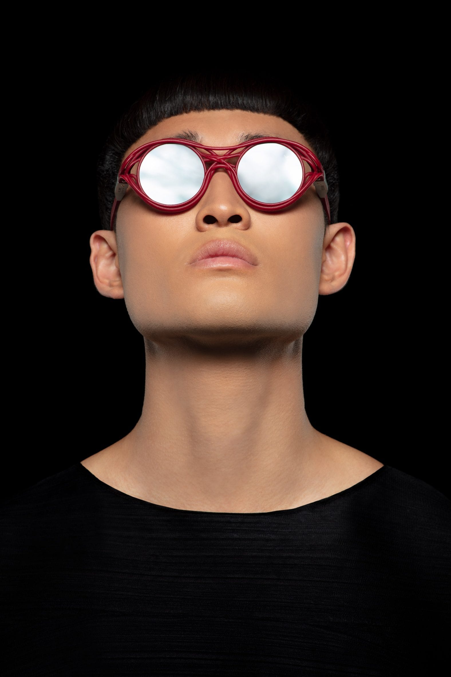 A man wearing a red pair of Kengo Kuma's sunglasses