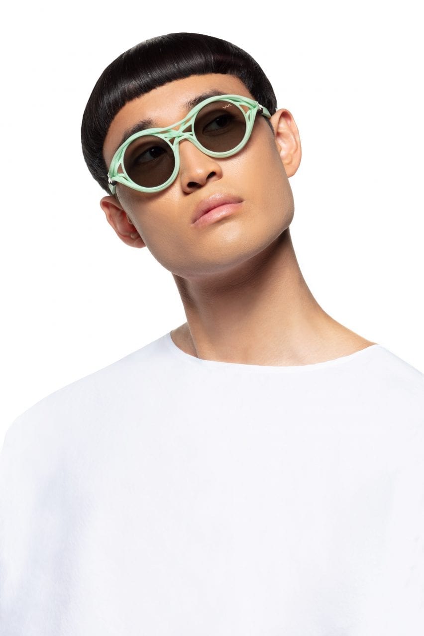 A man in a white top wears light green sunglasses