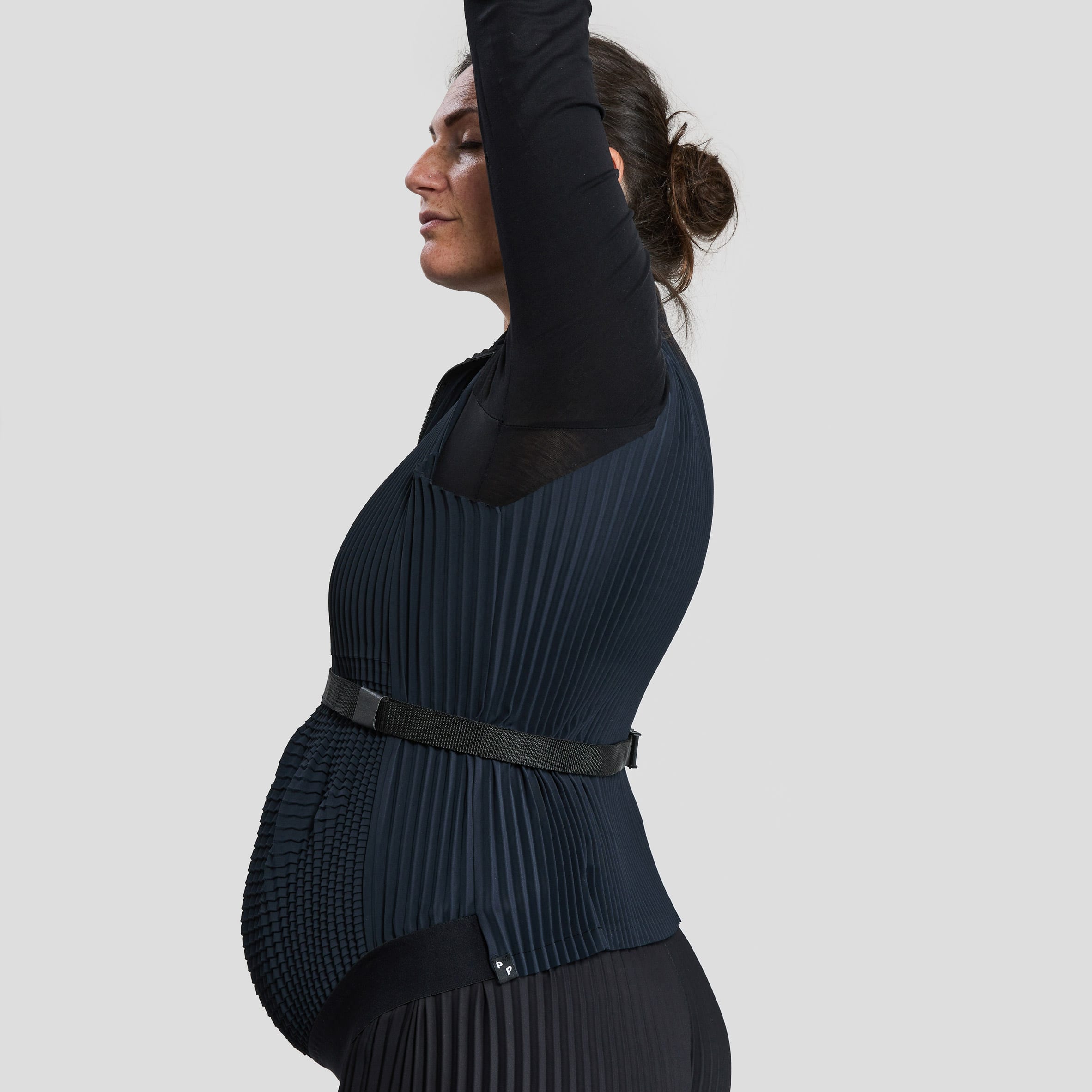 A pregnant woman wearing the Petit Pli clothes stretches
