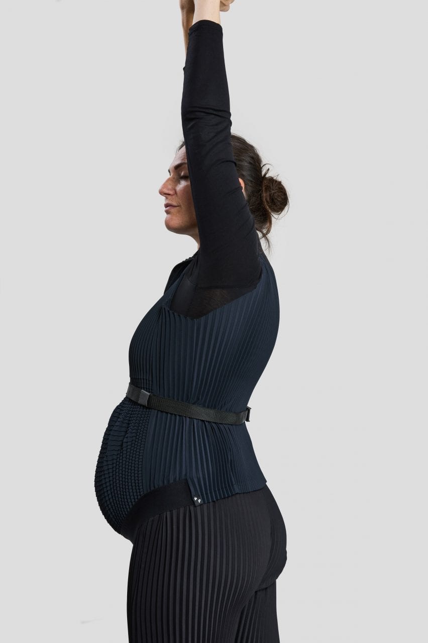 A pregnant woman wearing the Petit Pli clothes stretches