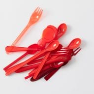 Red hued cutlery is placed in a pile