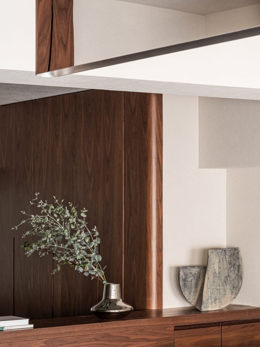 Lemari pakaian kayu walnut dengan vas dekoratif di apartemen berkonsep The Life